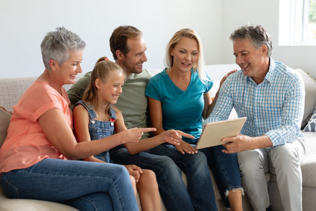 Smiling Caucasian grandparents sitting on a couch with their grandchild, symbolizing family connection and legacy.